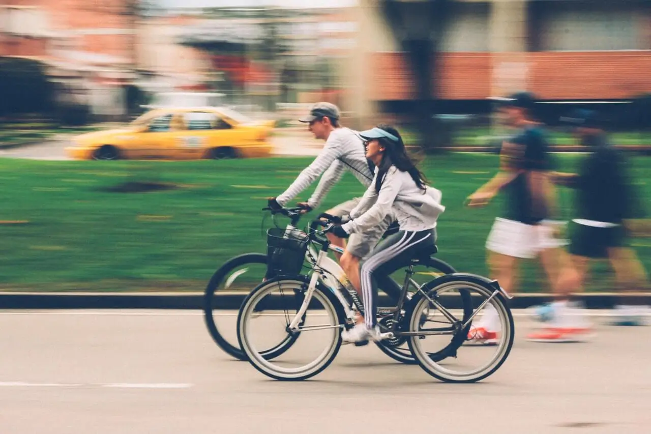 A man and woman riding cruiser bicycles with on a city street.